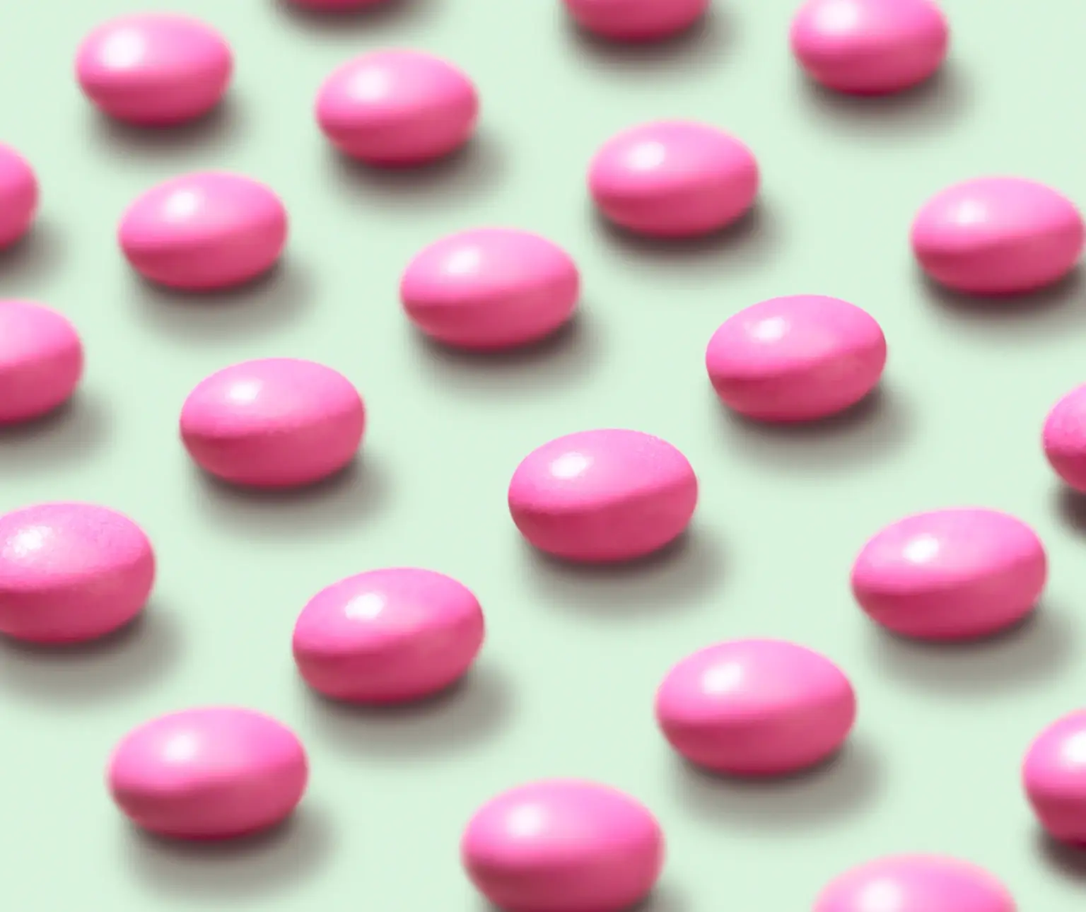 Rows of pink oval pills on a light green background.