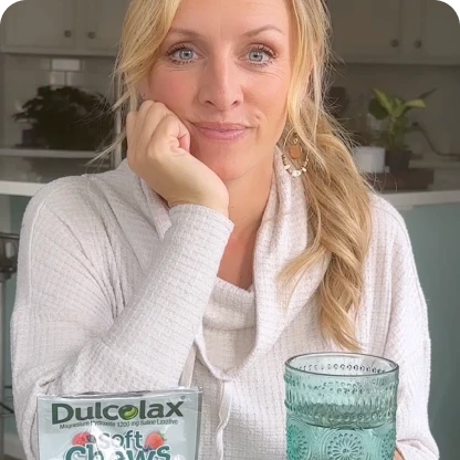 Person with long hair holds a glass next to Dulcolax Soft Chews laxative pack.