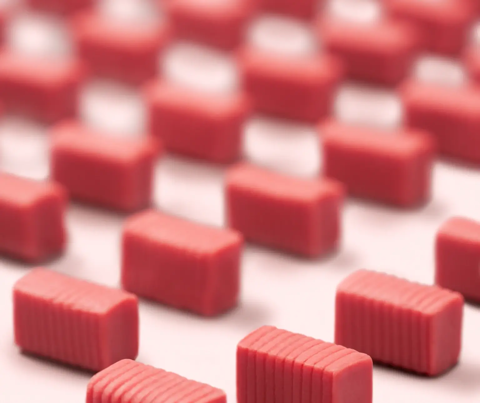 Rows of small, pink rectangular erasers on a light surface.