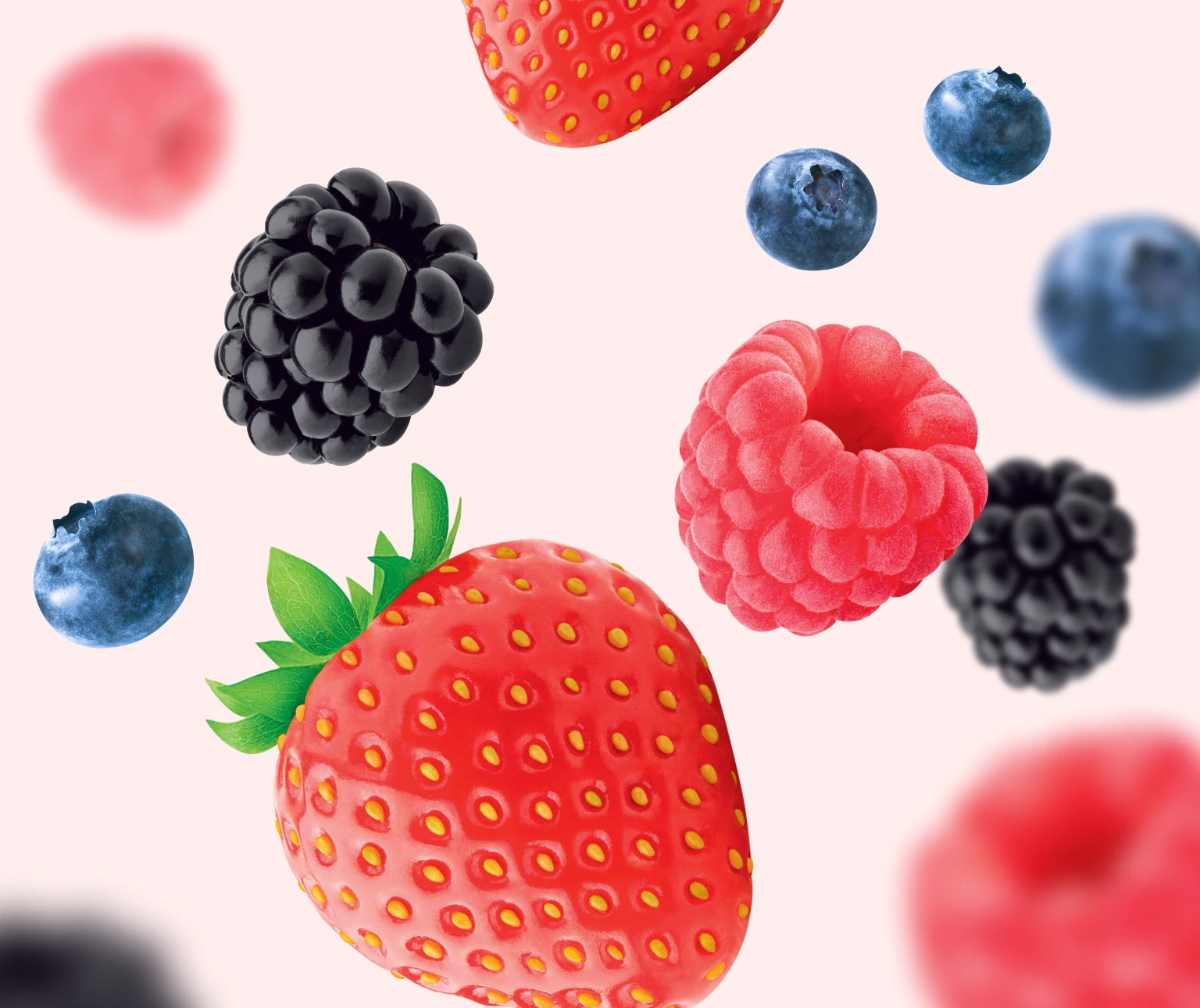 Photo d’une douzaine de petits fruits mélangés (fraises, bleuets, framboises et mûres) flottant sur un fond rose pâle pour mettre en valeur le goût délicieux et les arômes naturels des Soft Chews