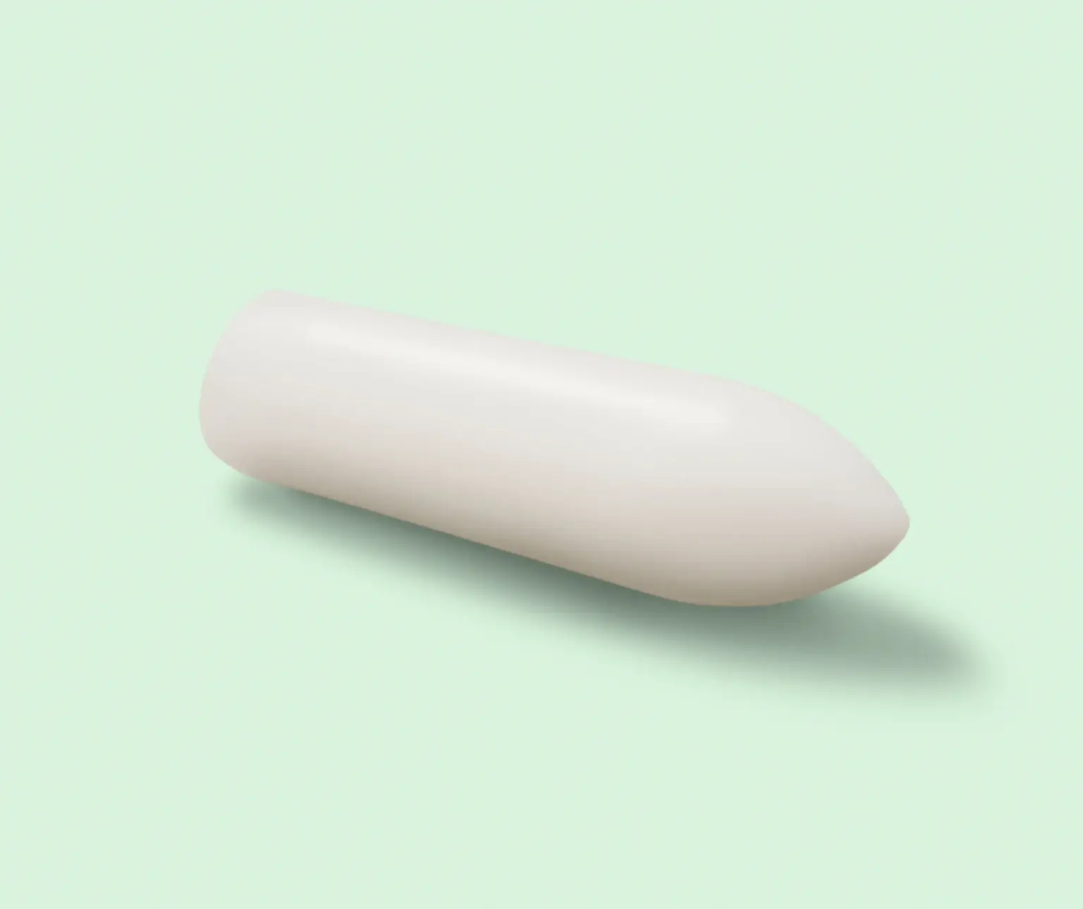 White cylindrical suppository on a light green background.