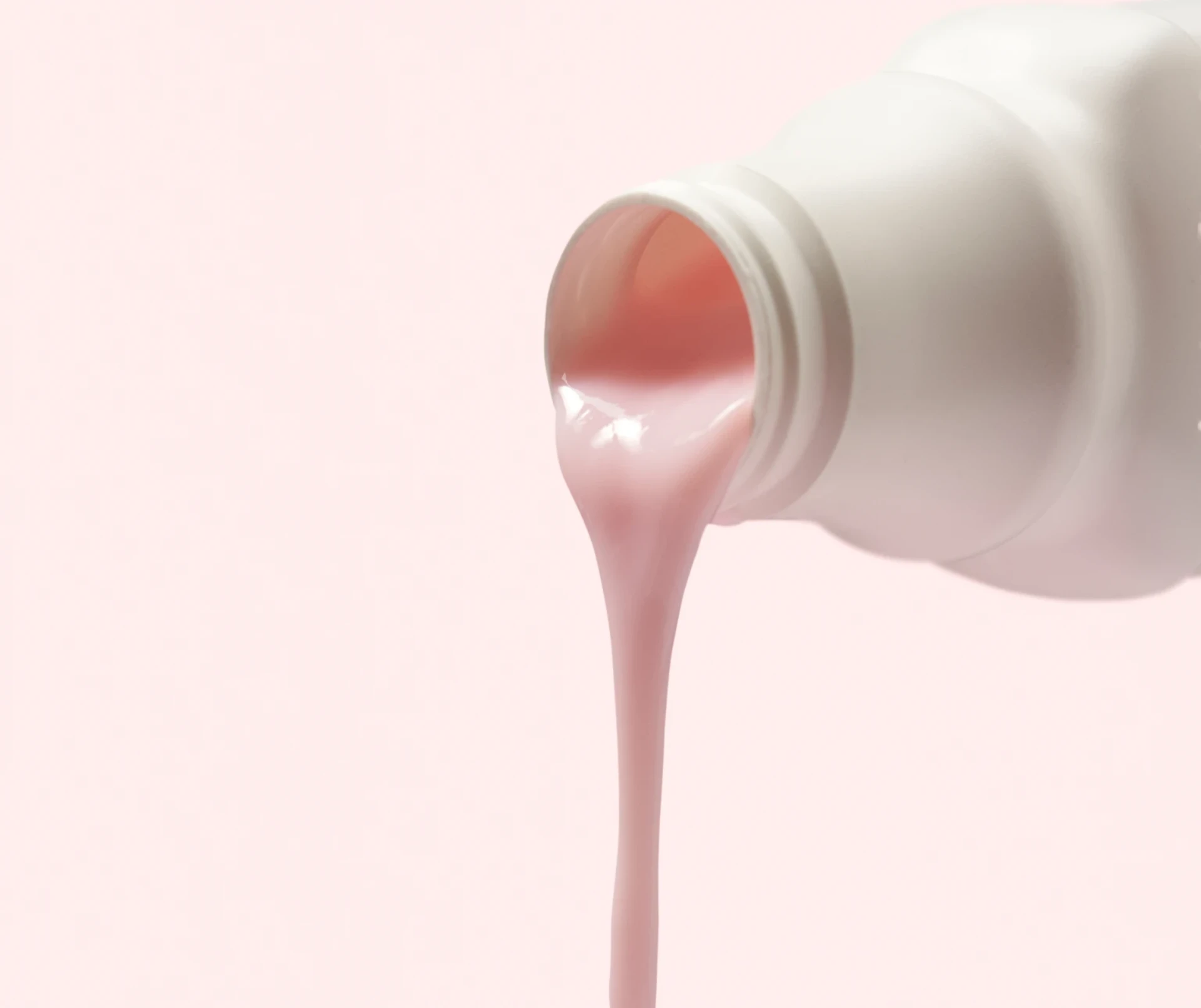 Photograph of a DulcoLax Liquid bottle being poured out in front of a light pink background.